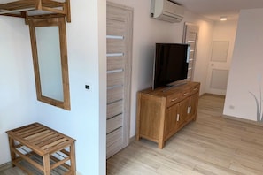 Ein Zimmer mit einem Holzkasten, einem Fernseher und einem kleinen Hocker.