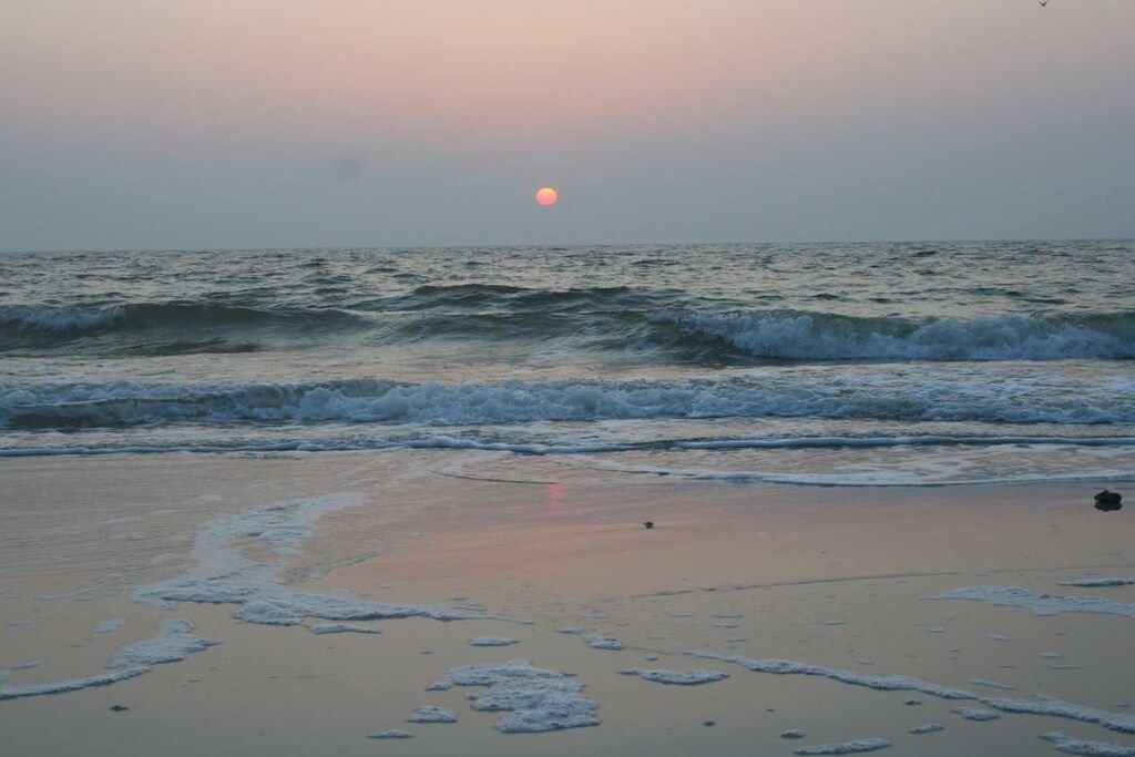 A beach with waves and a visible sun.