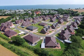 Ein Wohngebiet mit in einem Raster angeordneten Häusern, Straßen und einem Gewässer im Hintergrund.