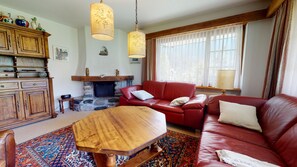 Ein Wohnzimmer mit Kamin, einem roten Ledersofa, einem Holztisch und einem gemusterten Teppich.