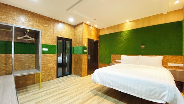 Une chambre d’hôtel avec un lit, une armoire, un miroir et une porte.
