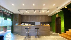 Une cuisine moderne avec un coin bar, deux tabourets et un mur d’accent de couleur verte.