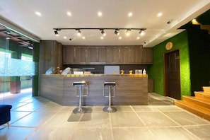 A modern kitchen with a bar area, two stools, and a green accent wall. - OYO 90262 Kota Kinabalu Homestay, Villa & Suite Boutique (Kota Kinabalu)