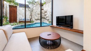 Una sala de estar moderna con un ventanal grande, una piscina, un sofá, una mesa redonda y un televisor de pantalla plana.