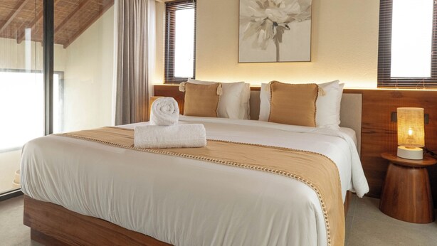 Un dormitorio amplio con una cama grande, cabecero de madera y techo con vigas a la vista.