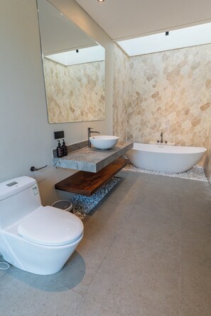 Ein modernes Badezimmer mit Toilette, Waschbecken und Badewanne.