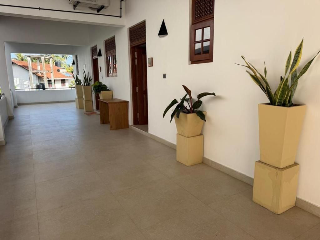 Un pasillo con suelo de baldosas, plantas en macetas y una puerta que da a otra habitación.