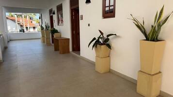 Un pasillo con suelo de baldosas, plantas en macetas y una puerta que da a otra habitación.