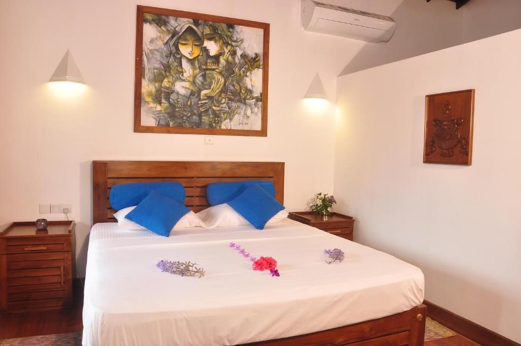 Una habitación de hotel con una cama de madera, un cuadro en la pared y una pequeña mesa con un florero.