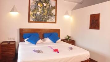 Una habitación de hotel con una cama de madera, un cuadro en la pared y una pequeña mesa con un florero.