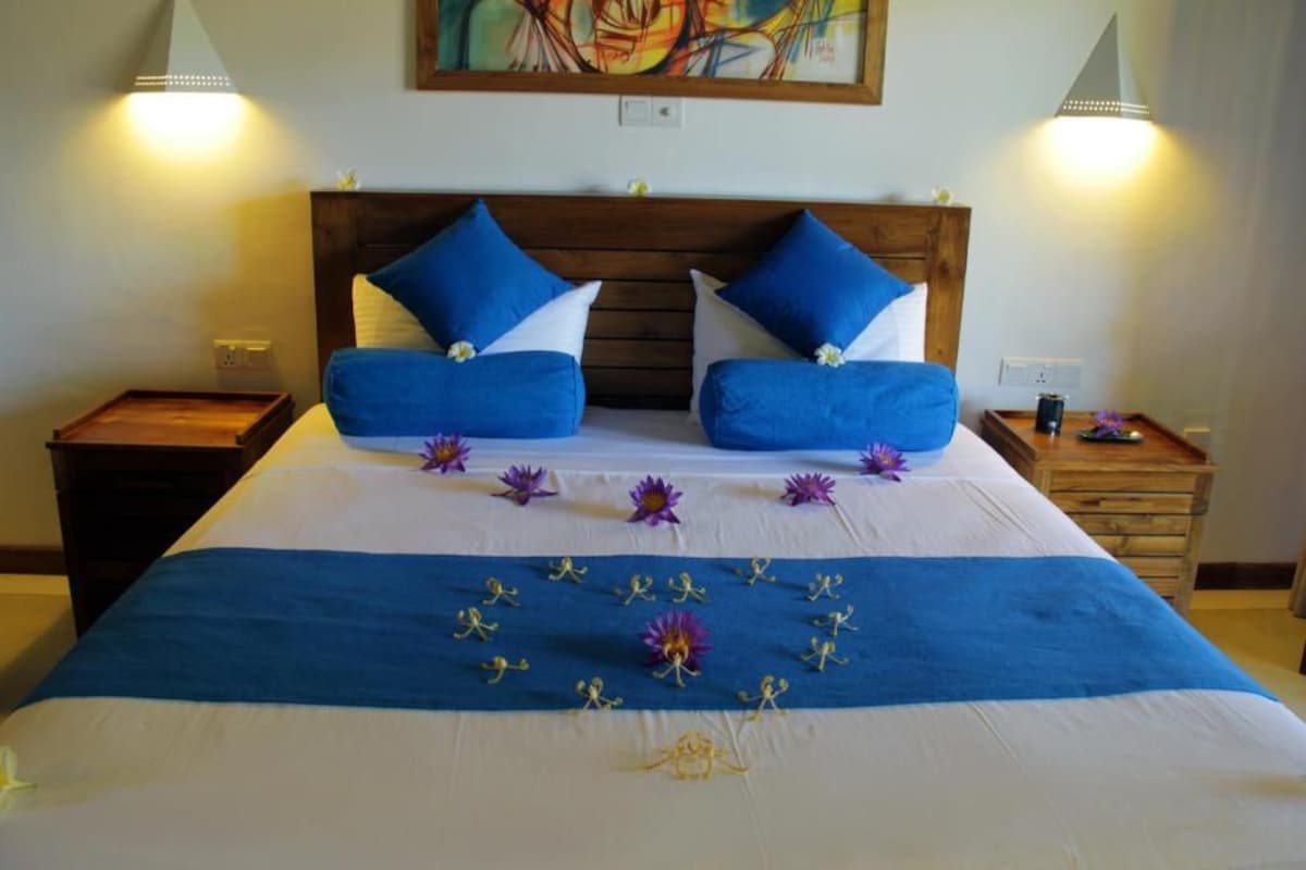 A neatly made bed with blue and white bedding, a wooden headboard, and decorative flowers.