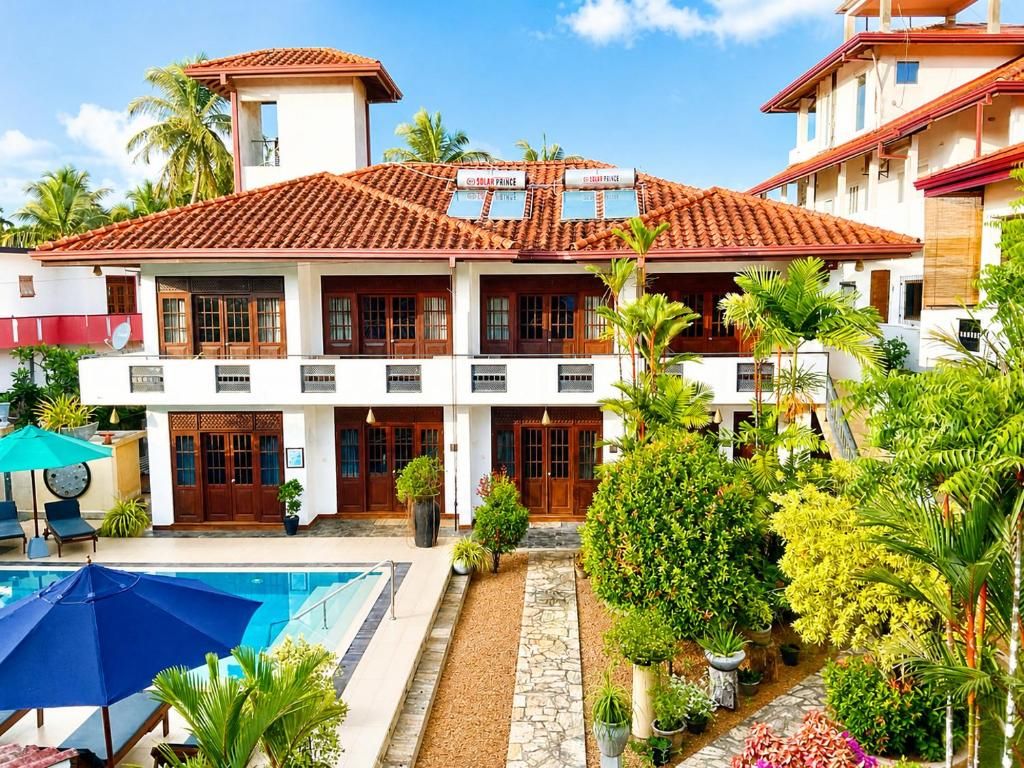 A two-story building with a tiled roof, a swimming pool, and a well-maintained garden with various plants.