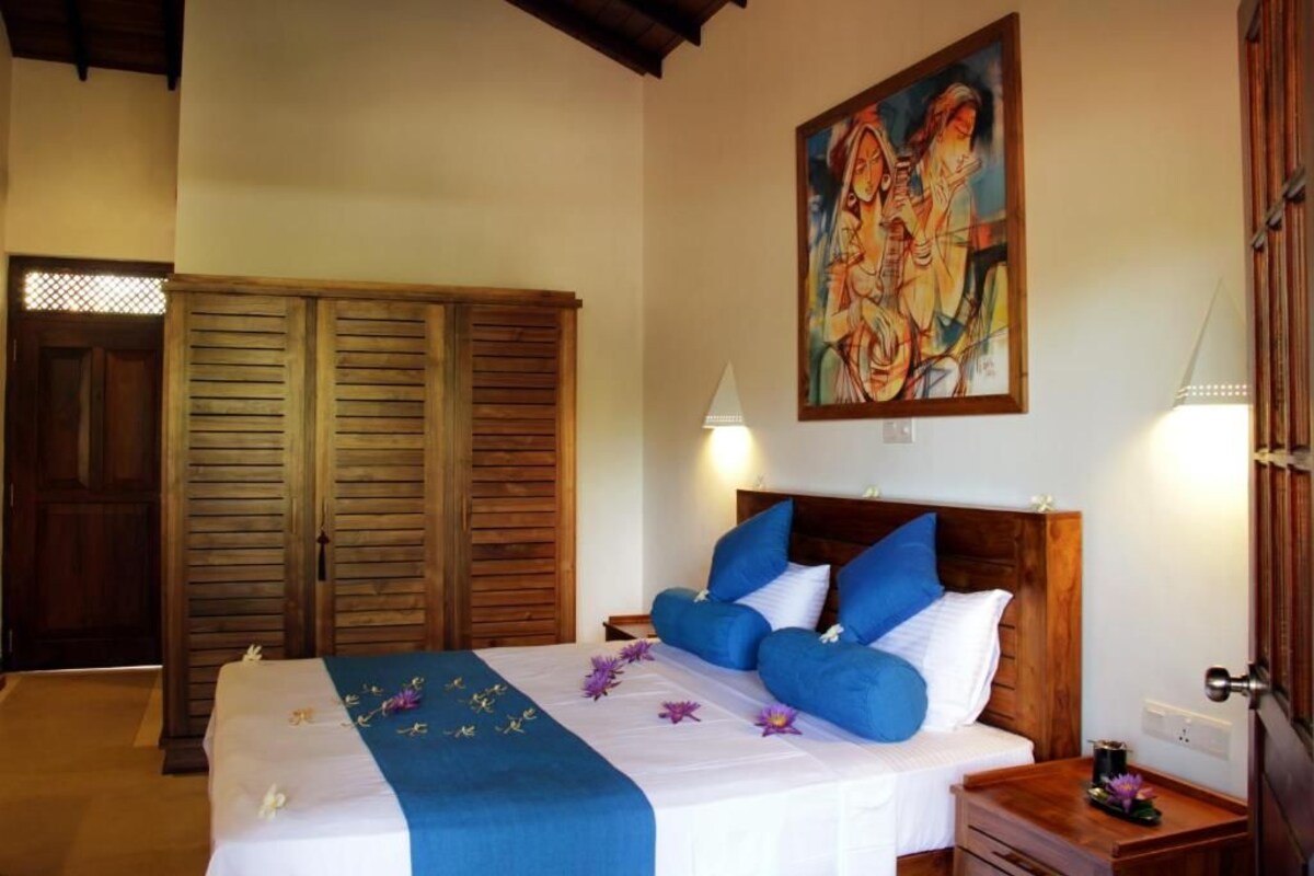 Quarto de hotel com cama, guarda-roupa de madeira e um quadro na parede.