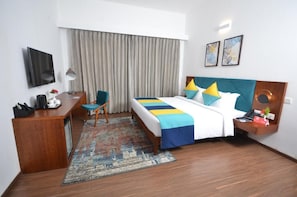 A hotel room with a bed, a desk, a chair, a TV, and a window with curtains. - Spree Resort at Century Wintersun (Bengaluru)