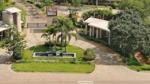 A landscaped area with a central building, palm trees, and a curved driveway. - Spree Resort at Century Wintersun (Bengaluru)