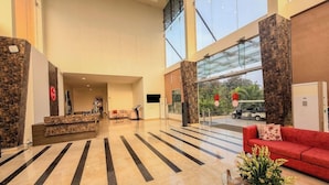 A spacious lobby with a reception desk, a red sofa, and a glass coffee table. - Spree Resort at Century Wintersun (Bengaluru)