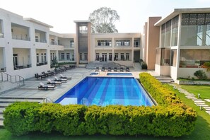 A hotel with a central swimming pool, multiple balconies, and a well-maintained garden. - Spree Resort at Century Wintersun (Bengaluru)