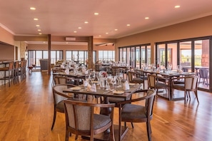 A spacious dining area with multiple tables and chairs, large windows, and a view of the outdoors. - Intle Boutique Hotel (Loerieheuwel)