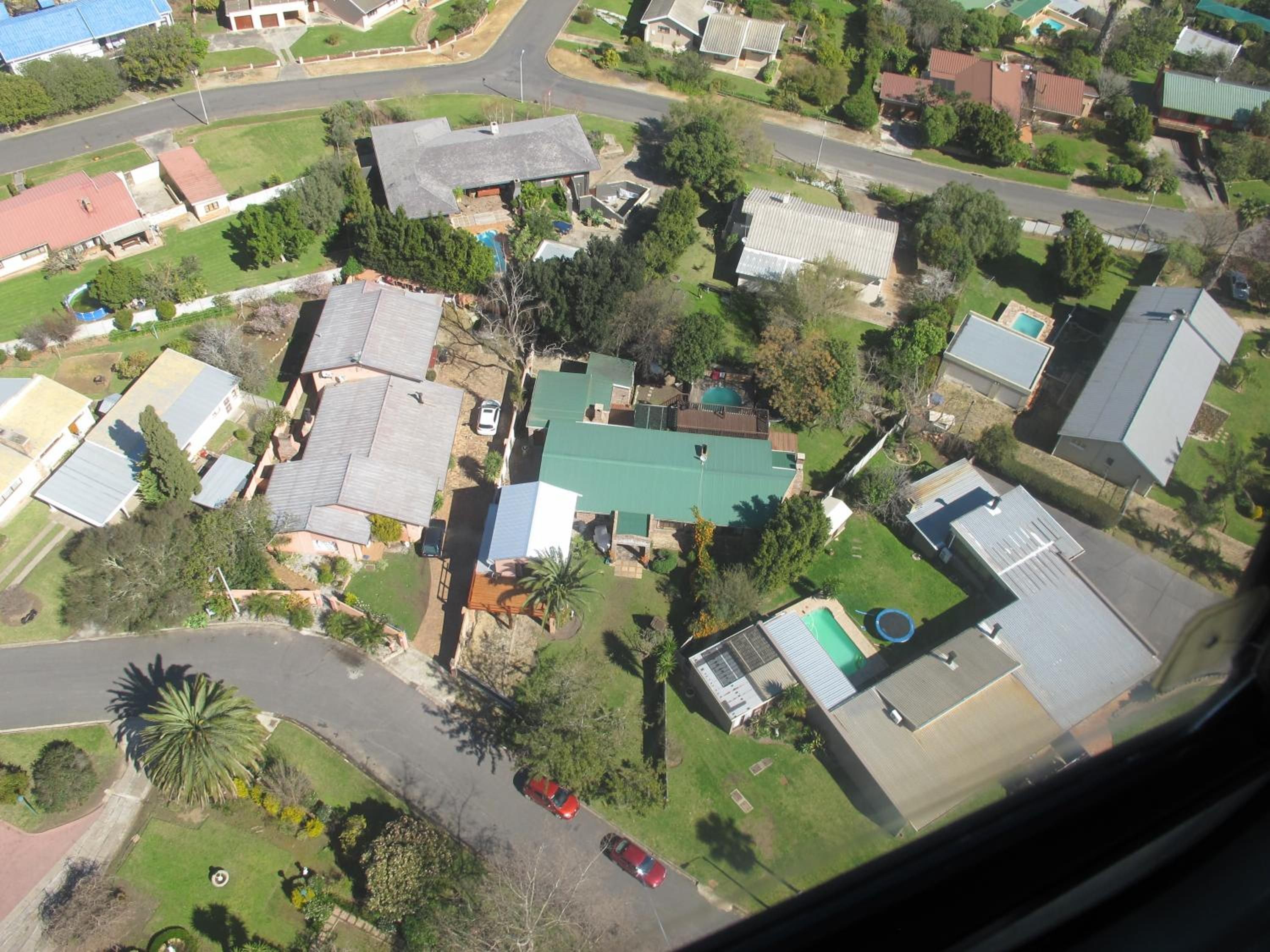 An aerial view of a residential area with houses, roads, and greenery.