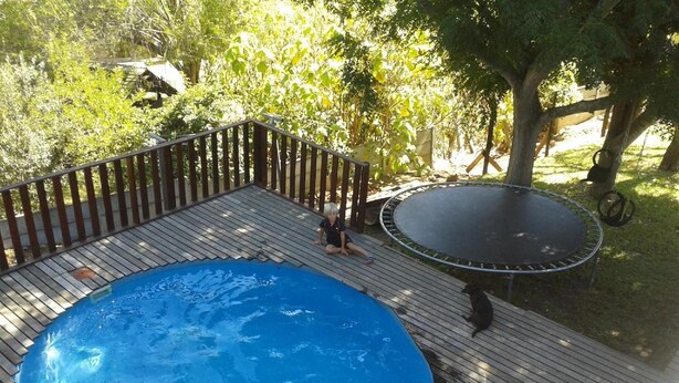 Een houten terras met een zwembad en een trampoline.