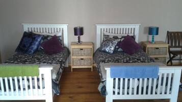 A room with two beds, each with a headboard, a bedside table, and a lamp.