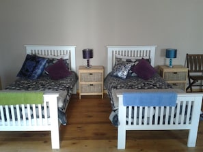 A room with two beds, each with a headboard, a bedside table, and a lamp. - Little Lotta Cottage (Caledon)