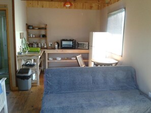 A compact room with a kitchenette, a dining table, and a sofa. - Little Lotta Cottage (Caledon)