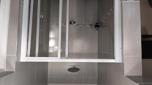A modern shower enclosure with a glass door, a showerhead, and a drain. - Wilson Guest House (Groblersdal)