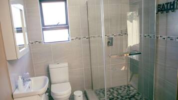 A bathroom with a toilet, sink, and shower.