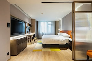 A hotel room with a bed, a desk, a TV, and a sliding door. - Hilton Huiting Xishuangbanna Jinghong (Xishuangbanna Dai)