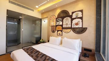 A hotel room with a bed, a glass shower enclosure, and wall art.
