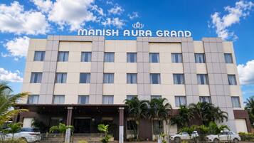 Un edificio de hotel con un letrero que dice 'MANISH AURA GRAND'.