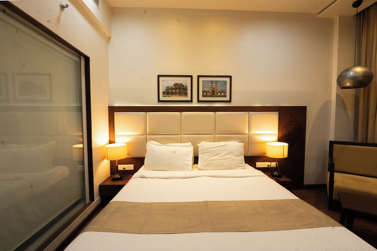 Ein Hotelzimmer mit einem großen Bett, zwei Nachttischlampen, einem Kopfteil mit Lichtleiste und zwei gerahmten Bildern an der Wand.
