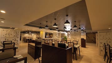 Un interior de restaurante moderno con techos altos, iluminación colgante y una combinación de asientos en cabinas y mesas.