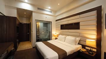 Una habitación de hotel con una cama grande, lámparas de noche, un escritorio y un armario.