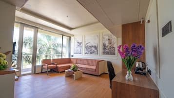 Amplia sala de estar con un ventanal, un sofá, una mesa de centro y un jarrón con flores.