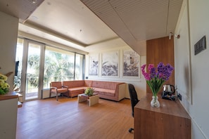 A spacious living room with a large window, a sofa, a coffee table, and a vase with flowers.