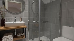 Een moderne badkamer met een douchecabine van glas, een wit wastafelmeubel en een toilet.