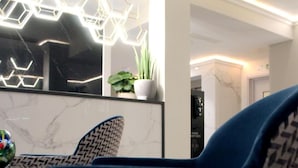 A modern interior with a reflective surface, geometric light fixtures, and a patterned chair. - NOX Waterloo (London)
