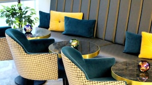 A seating area with woven chairs and a sofa, a glass coffee table, and decorative vases. - NOX Waterloo (London)