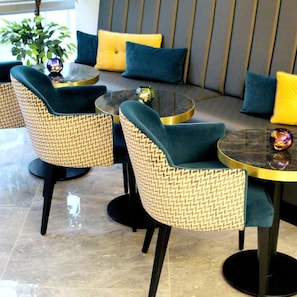 A seating area with woven chairs and a sofa, a glass coffee table, and decorative vases. - NOX Waterloo (London)