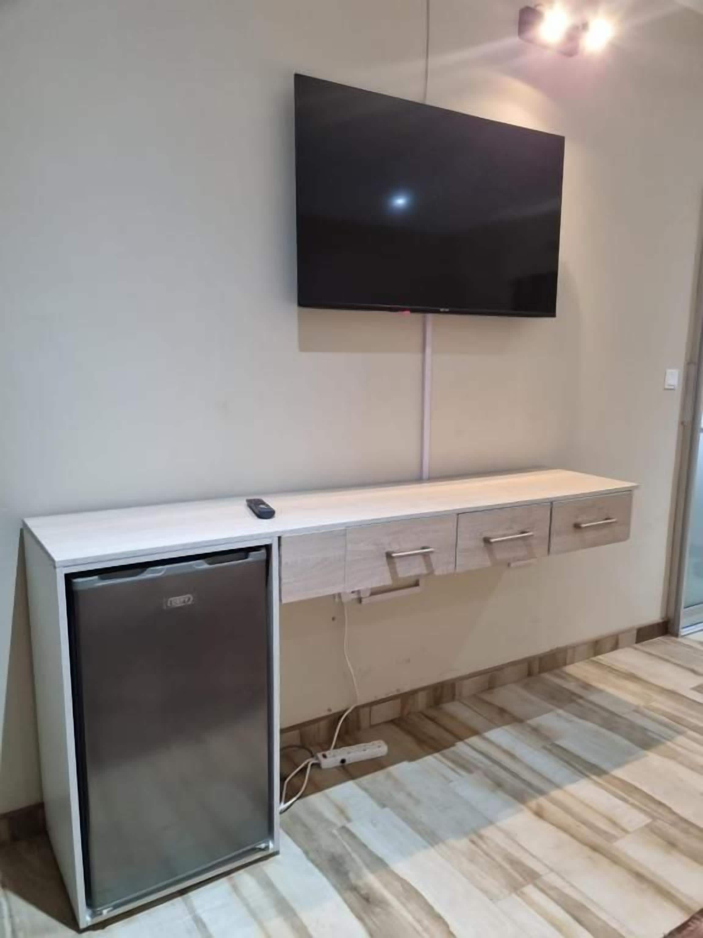 Ein an der Wand befestigter Flachbildfernseher über einem Holzschrank mit Schubladen.