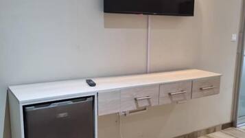 Ein an der Wand befestigter Flachbildfernseher über einem Holzschrank mit Schubladen.