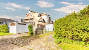 Een tweelaags huis met een schuin dak, een schotelantenne en een omheind oprit.