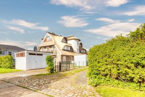 Een tweelaags huis met een schuin dak, een schotelantenne en een omheind oprit.