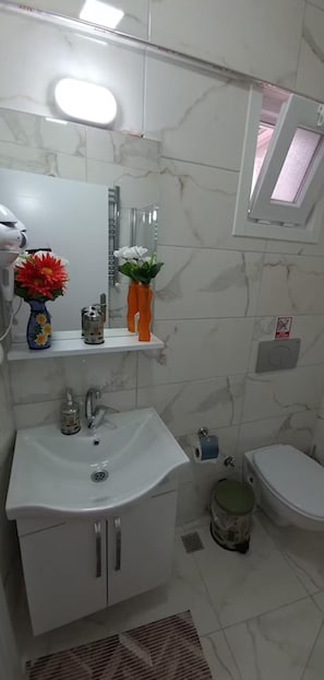 A bathroom with a white sink, mirror, and toilet. There are two flower vases on the sink. - Leydi Pansiyon Büyükada (Adalar)