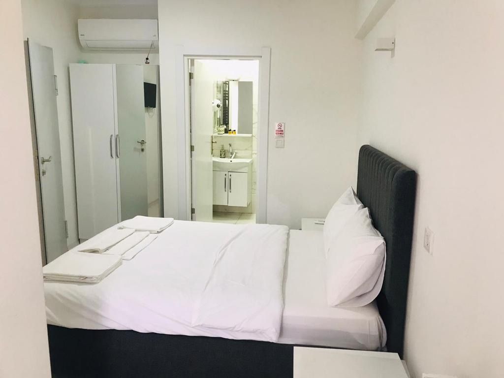 A hotel room with a bed, a bedside table, a wardrobe, and a bathroom visible through an open door.