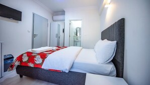 Ein modernes Hotelzimmer mit einem Bett, einem an der Wand befestigten Flachbildfernseher und einer Tür zu einem Badezimmer.