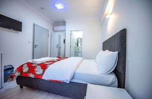Ein modernes Hotelzimmer mit einem Bett, einem an der Wand befestigten Flachbildfernseher und einer Tür zu einem Badezimmer.