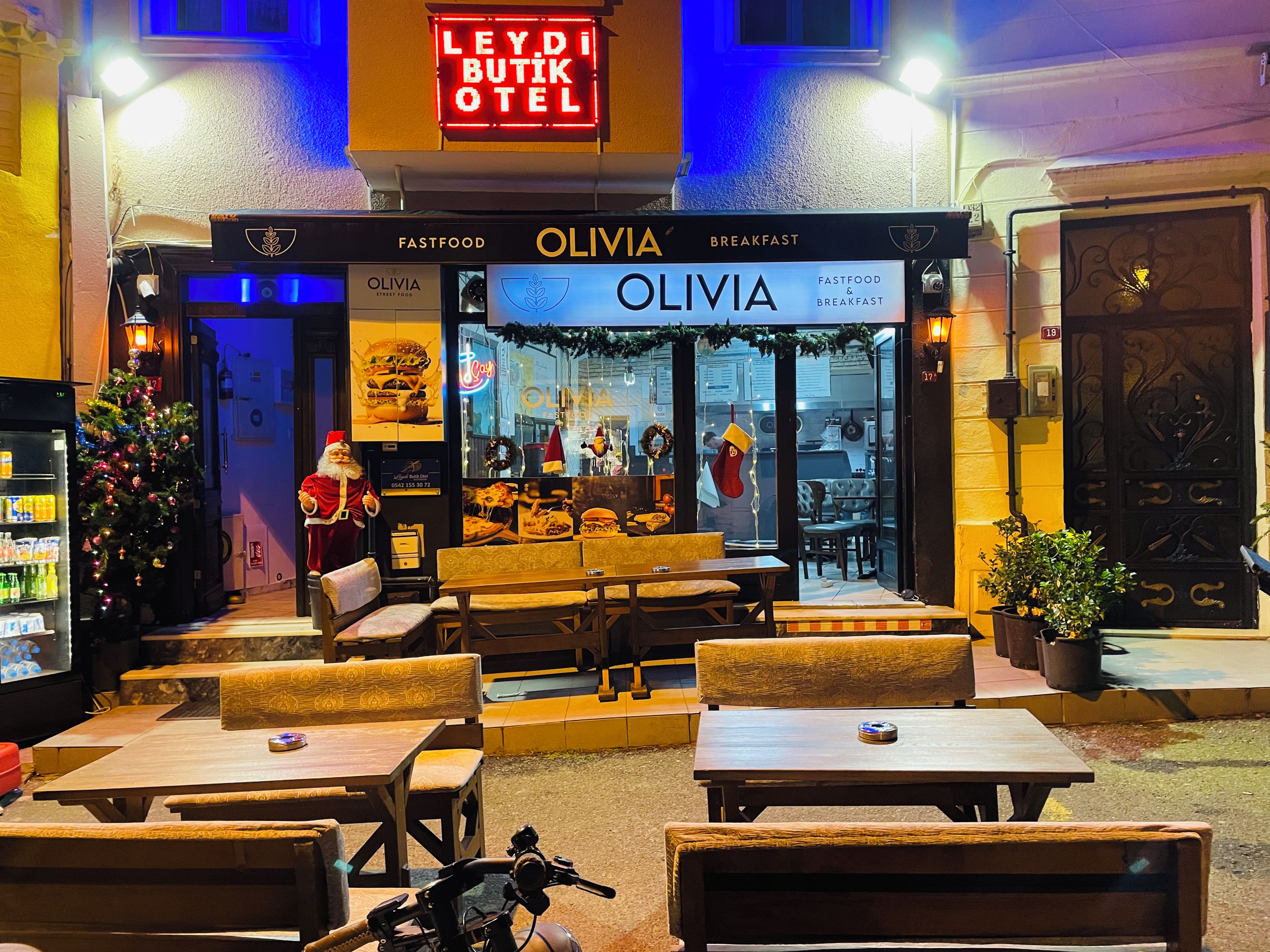 A restaurant named OLIVIA with outdoor seating and a Christmas decoration.